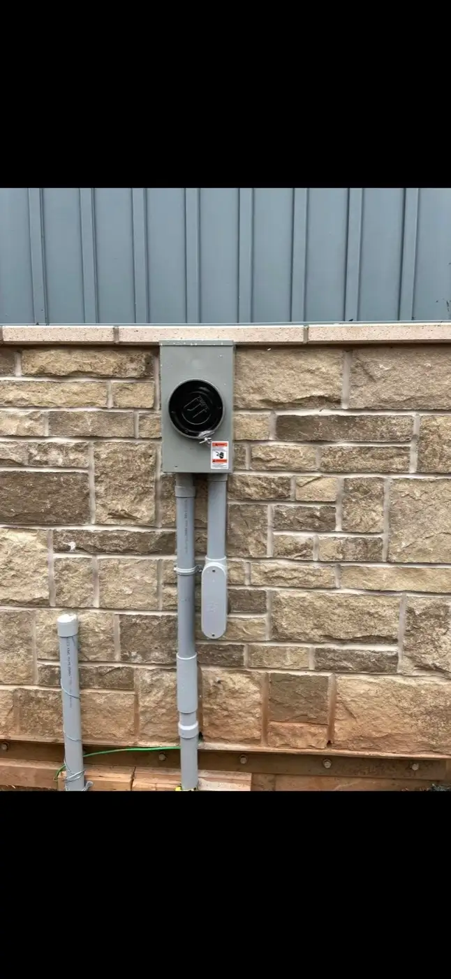 New meter base and conduit installed on a stone foundation