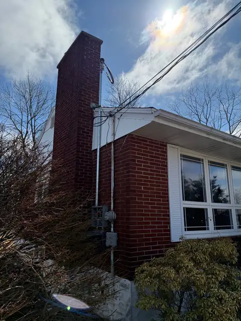 Completed service mast and meter on a brick bungalow beside the chimney
