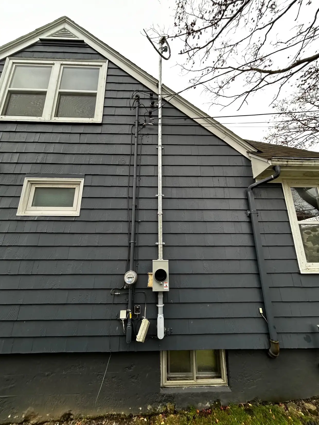 Completed service mast, meter base and overhead drop on a shingled Halifax house