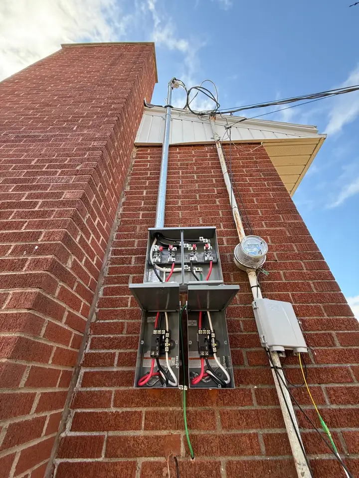 Service mast, meter and disconnects on a brick two-unit, looking up to the overhead drop